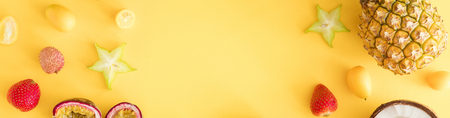 Backdrop or banner of exotic tropical fruits background with copyspace. Colorful fresh exotic fruits on yellow desk. Pineapple, coconut, passion fruit, strawberry, carambola. Flat lay, top viewの写真素材