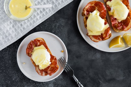 Top view of bruschetta with parma ham and Egg Benedict. Classic Eggs Benedict with bacon, hollandaise sauce, view from aboveの写真素材