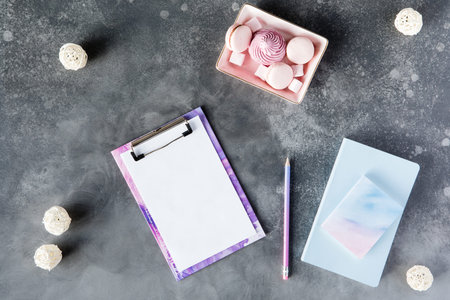 Flat lay of office stationery with cup of tea with marshmallow and laptop on a gray background with...