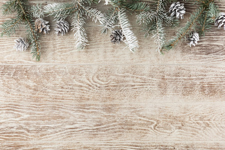 Christmas fir tree with pine cones and snow on wooden white board. Christmas reindeer carrying a...