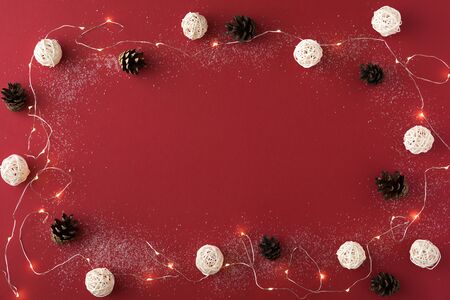 Christmas composition with garland and white balls on red background. Flat lay of Christmas, winter, new year concept. Top view and copy spaceの写真素材