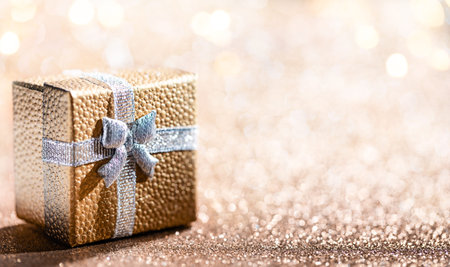 Gold gift box with magical light on glitter bokeh background. Christmas holidays.