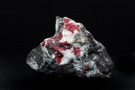 Real raw red Cinnabar stone chunk macro isolated on black surfaceの写真素材
