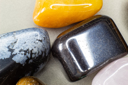 Colourful tumbled gemstones on a black surface huddled together in one set. Macro gemstone shotの写真素材