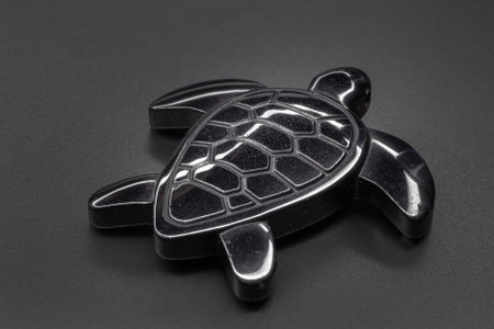 Macro deep grey hematite carved turtle isolated on grey backgroundの写真素材