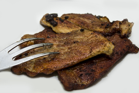 Roasted meat with meat fork isolated on whiteの写真素材