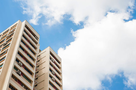 A tall modern residential tower block against a clear blue sky.