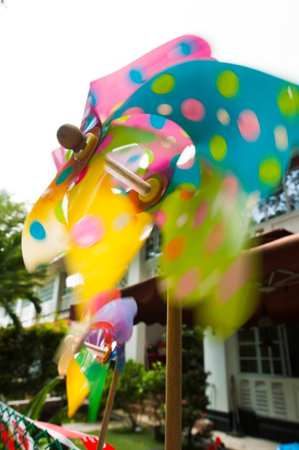 Close up of a colorful pinwheel spinning with a strong breeze in front of a house.