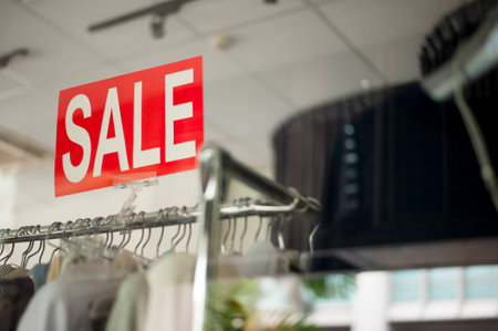 Shopping time! A sale sign mounted on a clothing rail that displayed all the beautiful dresses.の写真素材