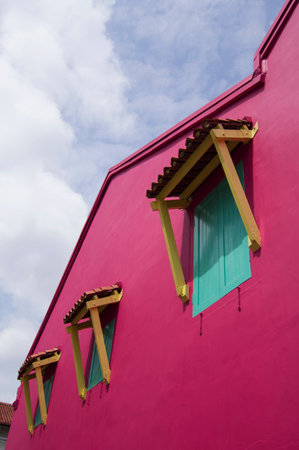 Cropped shot of some windows on a pink wall, against a clear blue sky.の写真素材