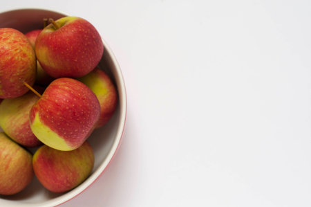 A close-up shot of some red apples on a bowl isolated on a white backgroundの写真素材