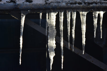 Icicles on the roof winter sunny eveningの写真素材