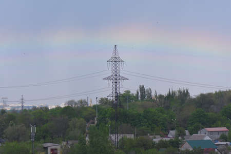 high voltage power lines in front of rainbowの写真素材