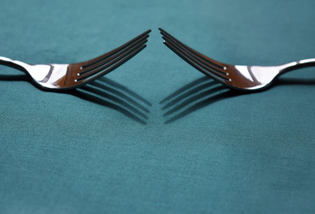 two metal forks on green background