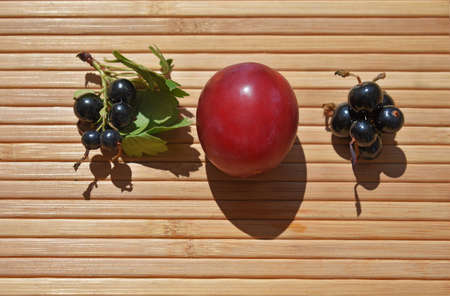 plum and black currant on wooden backgroundの写真素材