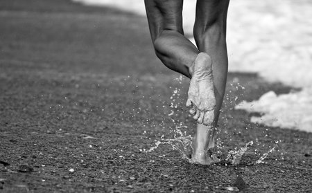Female feet in water. Black and white photo with shallow depth of field.