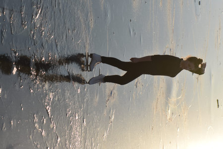 Silhouette of a woman in swimsuit jumping on a frozen surfaceの写真素材