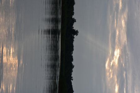 Reflection of the clouds in the water of a lake in the eveningの写真素材