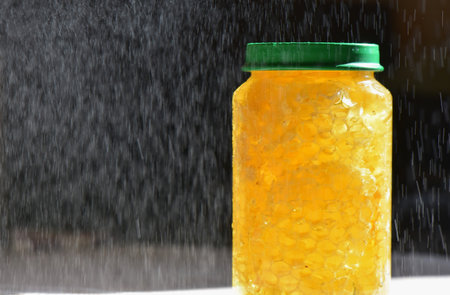 Honey in a jar with water splashes on a white backgroundの写真素材
