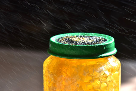 Honey in a jar with drops of water on a dark backgroundの写真素材