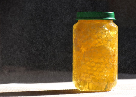 Honey in a glass jar with a green lid on a black backgroundの写真素材