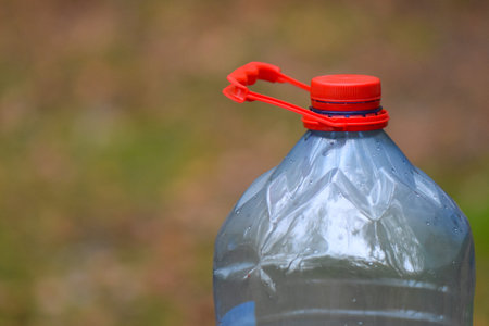 Plastic bottle of water with red cap on blurred background.