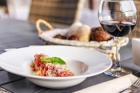 Italian pasta with tomatoes, cheese and a sprig of basilの写真素材