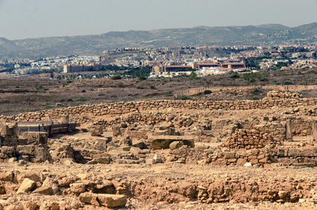 White lighthouse on background of mountains and ancient ruins in the Archaeological Park of Paphos,...