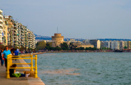 Thessaloniki, Greece - March 26, 2017: People walking on the coast in Thessaloniki next to the White...