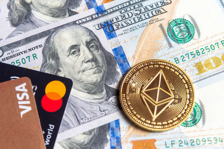 Gold Ethereum crypto currency with visa and mastercard cardson US dollars. Digital cryptocurrency close-up. Exchange, bussiness, and commercial. Profit from mining crypto currencies. Miner with dollars and gold ethereum coin.のeditorial素材