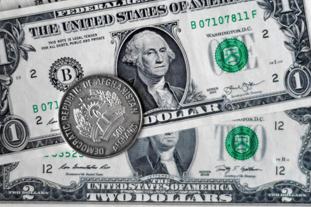 Afghani coin (Afganistan money) on top of dollar bills for financial and investment conceptsの写真素材