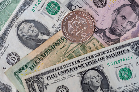 Afghani coin (Afganistan money) on top of dollar bills for financial and investment concepts