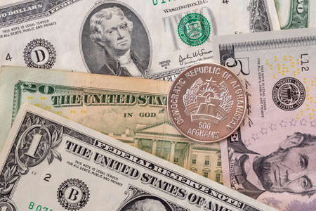 Afghani coin (Afganistan money) on top of dollar bills for financial and investment conceptsの写真素材