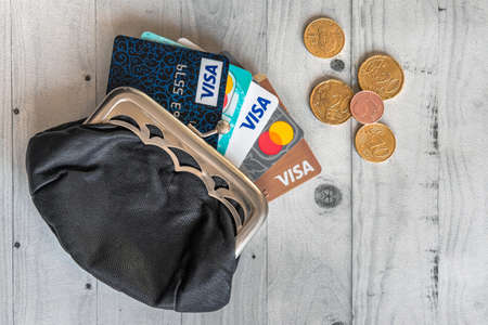 Moscow, Russia, January 17,2021 - Few credit cards (Visa, Mastercard and Mir) in the leather vintage wallet coin-box at wooden table, product concept shot.のeditorial素材