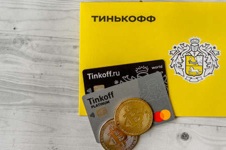 Moscow, Rissia - February 11, 2021: Bitcoin, Black and Platinum Tinkoff Bank debit card and corporate yellow envelope (text translation from russian: Tinkoff). Russian commercial bank founded by Oleg Tinkov.のeditorial素材