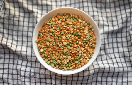 Assorted set of beans, legumes, peas, lentils laid out in the shape of a heart on a white ceramic cup on a backgroundの写真素材