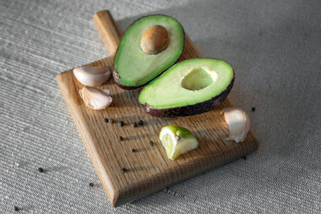 Closeup of some raw fruits and vegetables to prepare a guacamole, such as avocados, garlic and lime...