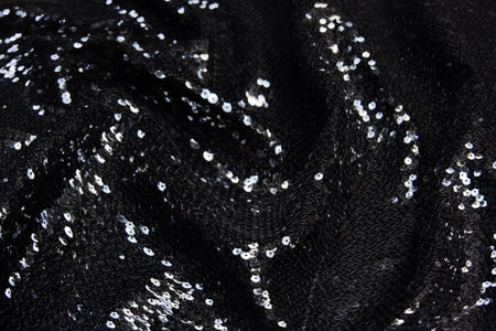 Silver sequin pattern. Sequins on black wool or jersey fabric as background.