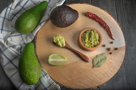 Fresh guacamole on a dish placed on a cutting wooden board with ingredients for homemade guacamole:. Top view. Concept of traditional Mexican preparation.の写真素材
