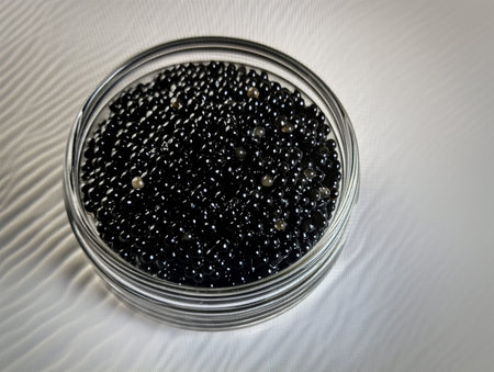 Black caviar in a petri dish on a white background.の素材