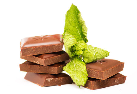 Chocolate squares with mint leaves on a white background.