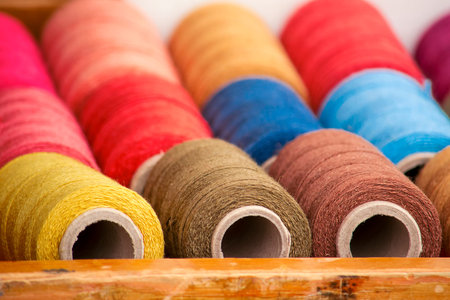 Sewing threads of different colors stacked in a drawer.