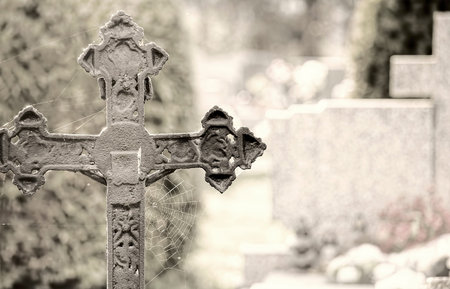 Cemetery with cross and spiderweb in the foreground.