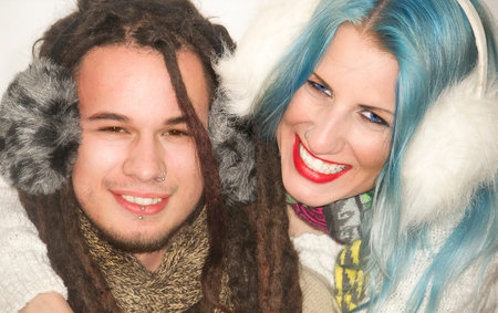 Cute young couple laughing in winter clothes on a white background.