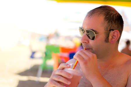 Man drinking a cocktail in a beach bar.の写真素材