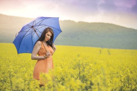 Brunette woman with an umbrella on a flower field.の写真素材