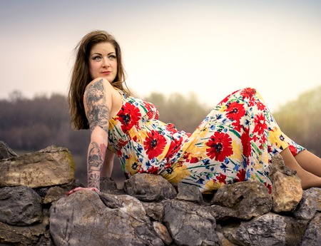 Woman in a floral dress posing on a rockの写真素材