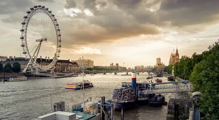 London, England - July 26, 2014 - Sunset in London over the Thames river in Westminster with the London eye and Big ben in the background. London is the capital city of England and a popular tourist destination.のeditorial素材