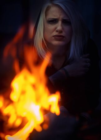 Blonde woman sitting in front of the fireの写真素材