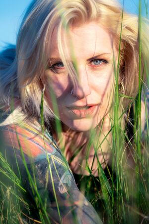 Pretty blonde woman with tattoos in the grassの写真素材